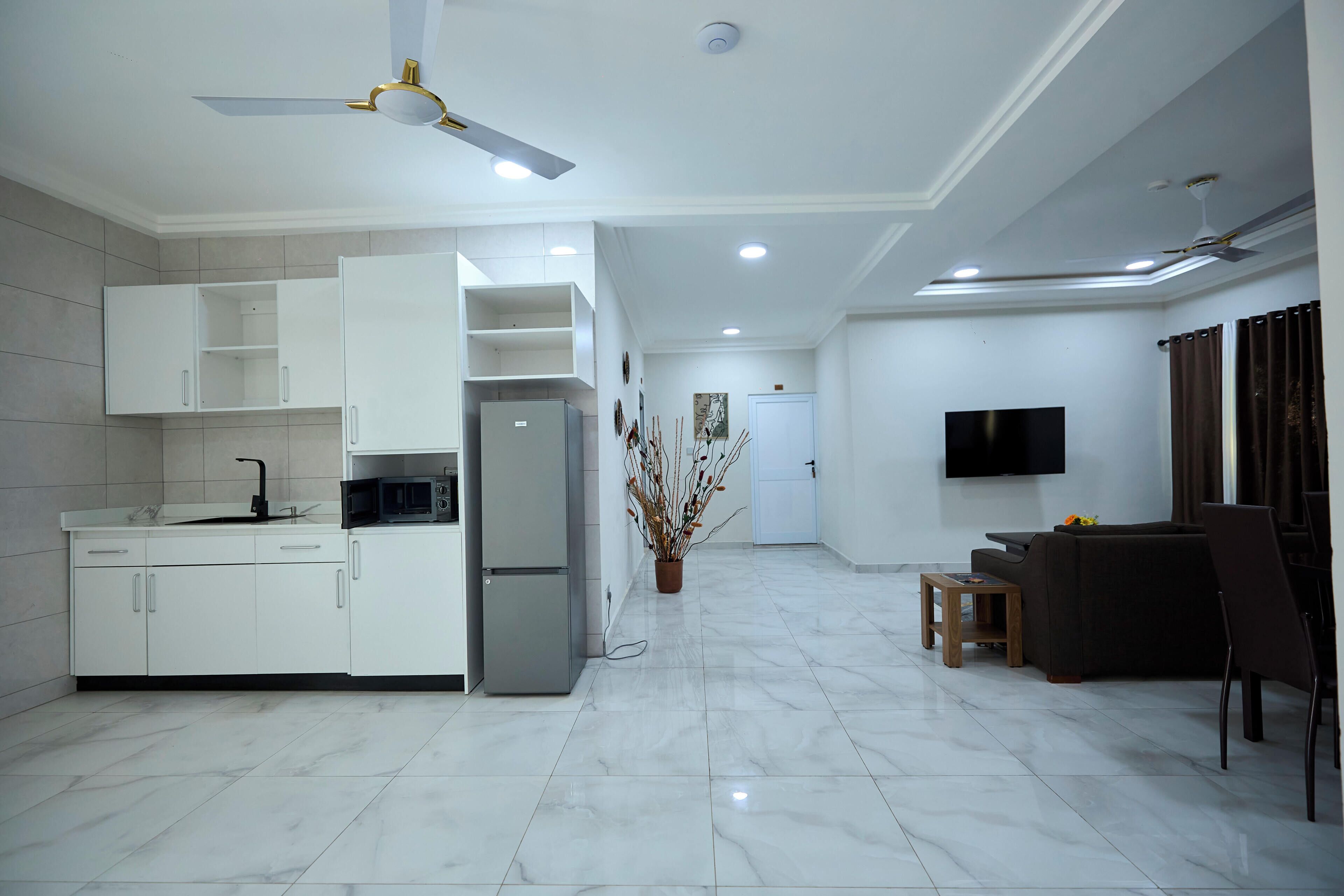 Una cocina moderna con armarios blancos, microondas integrado y refrigerador.