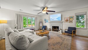A living room with a sofa, chairs, a fireplace, a television, and a large window.
