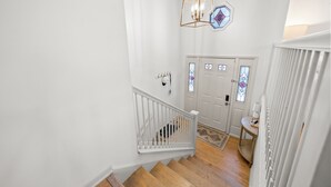 A staircase with white railings leading to a door with stained glass windows.