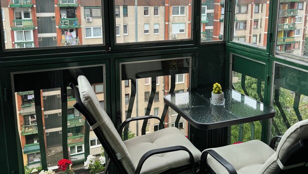 A balcony with two chairs and a small table, overlooking a residential area with multi-story buildings. - Charming 1-bedroom apartment in brilliant Sarajevo with WiFi, AC (Sarajevo)