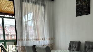 A dining area with a glass table, grey upholstered chairs, a white table base, and a patterned rug. - Charming 1-bedroom apartment in brilliant Sarajevo with WiFi, AC (Sarajevo)