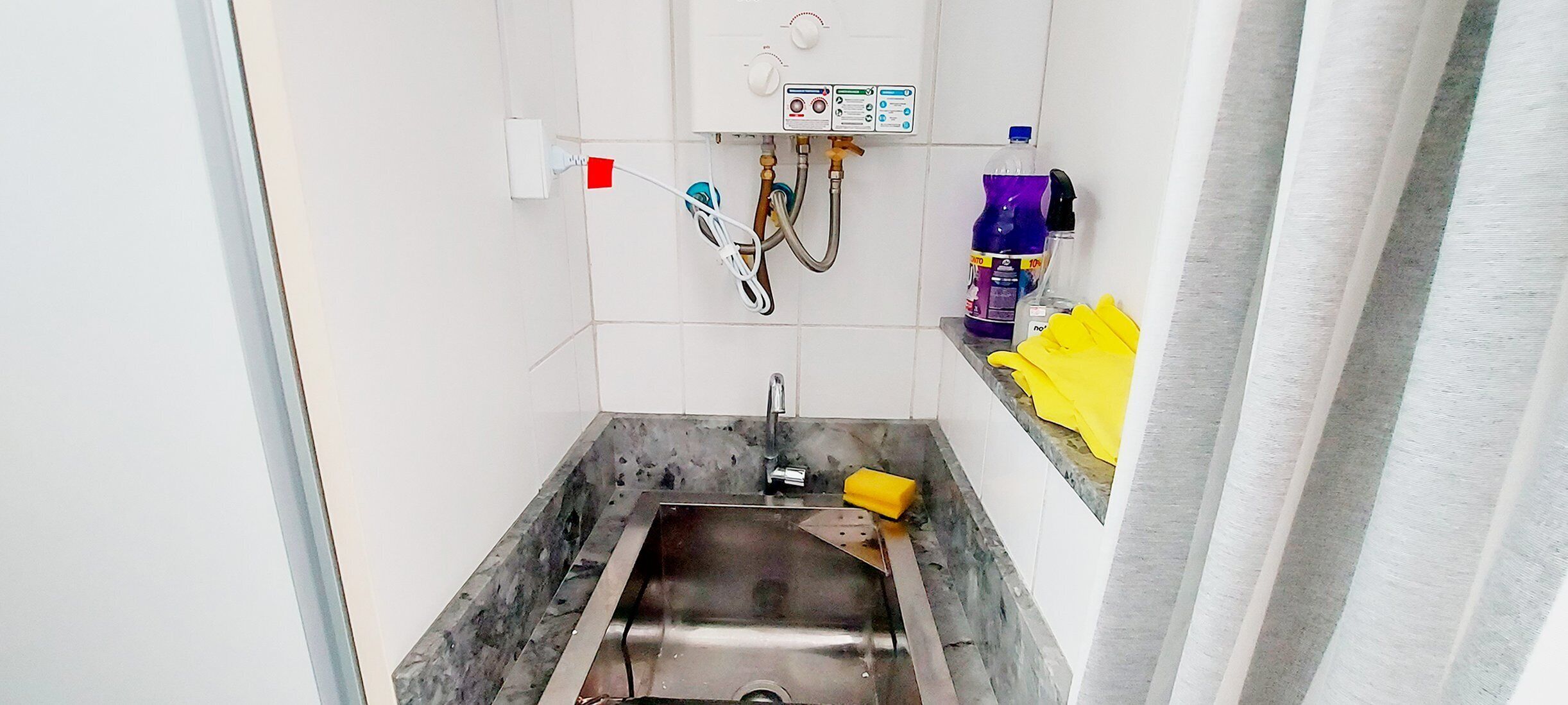Ein Badezimmer mit Waschbecken, Wasserhahn und Bedienfeld für den Warmwasserbereiter.