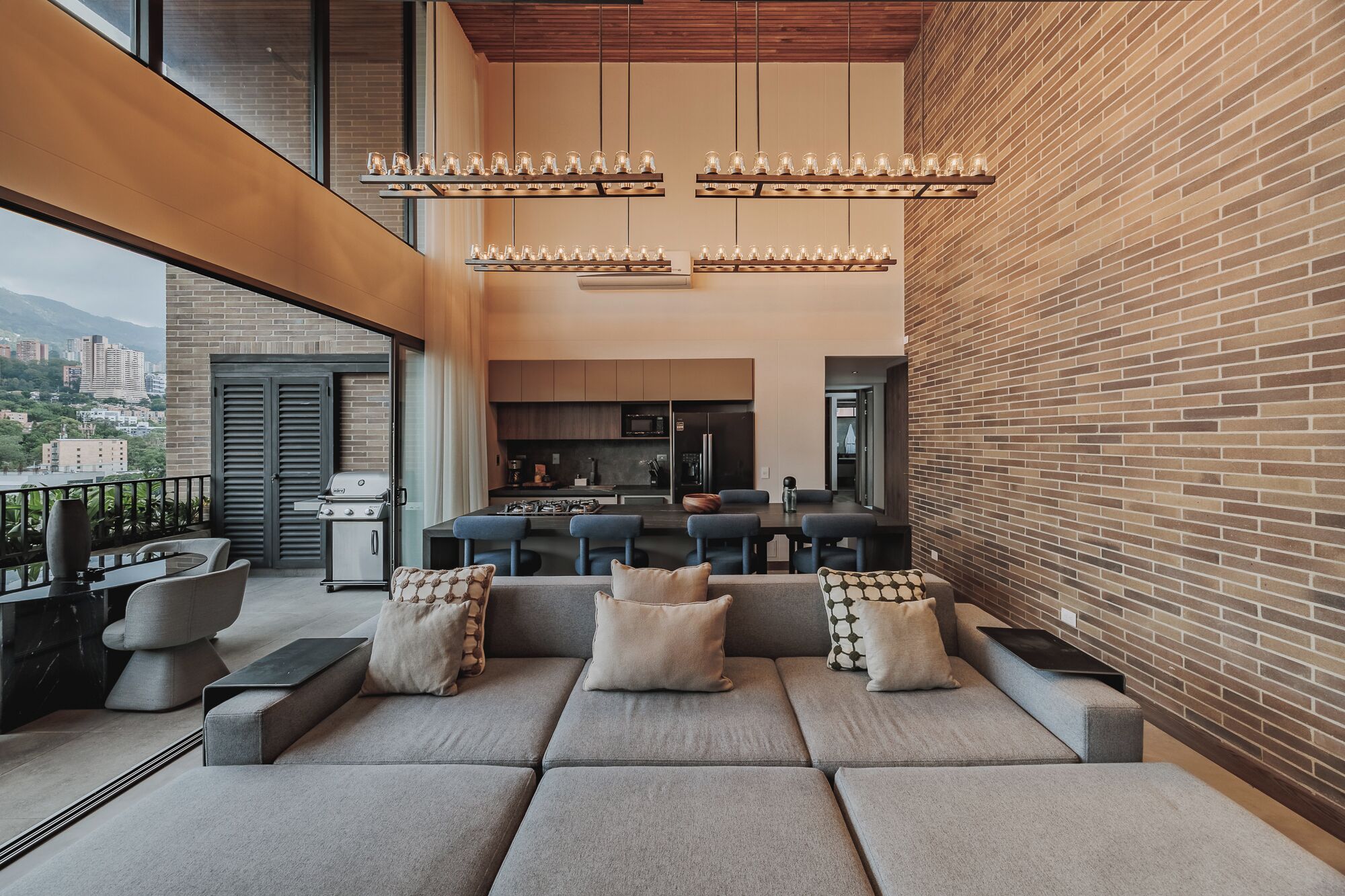A modern living room with a sofa set, a dining area, and a kitchen.