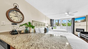 A hotel room with a kitchen area, a large bed, a ceiling fan, and a view of the outdoors. - Top of the Gulf 110 (Panama City Beach)