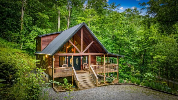 Een vakantiehuis in blokhutstijl met een veranda, een trap en uitzicht op het omliggende bos.
