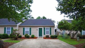 A two-story residential building with a front driveway, green shutters, and a well-maintained lawn. - Cheerful 2 bedroom 2bath townhouse (14hv) (Columbia)