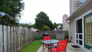 A backyard with a wooden fence, a barbecue grill, and a table with chairs. - Cheerful 2 bedroom 2bath townhouse (14hv) (Columbia)