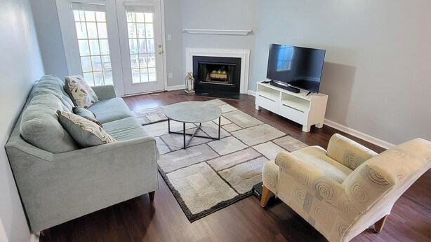 A living room with a sofa, armchair, coffee table, TV, fireplace, and a ceiling fan. - Cheerful 2 bedroom 2bath townhouse (14hv) (Columbia)