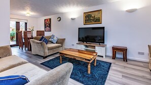 Ein modernes Wohnzimmer mit Sofa, Couchtisch, Fernseher und Kunstwerken an den Wänden.