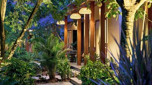 A well-maintained garden pathway leading to a building with a traditional design, featuring columns and hanging lamps. - Mua Valley Lodge (Ninh Binh)