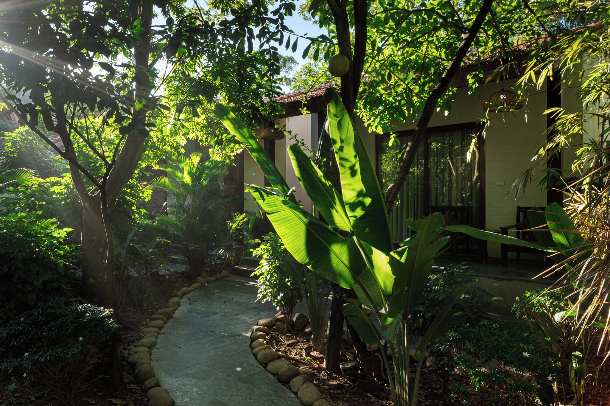 Un sendero de jardín que conduce a un edificio con techo de tejas y una pared de piedra.