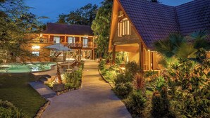 A two-story building with a swimming pool, surrounded by lush greenery and a well-lit pathway. - Mua Valley Lodge (Ninh Binh)