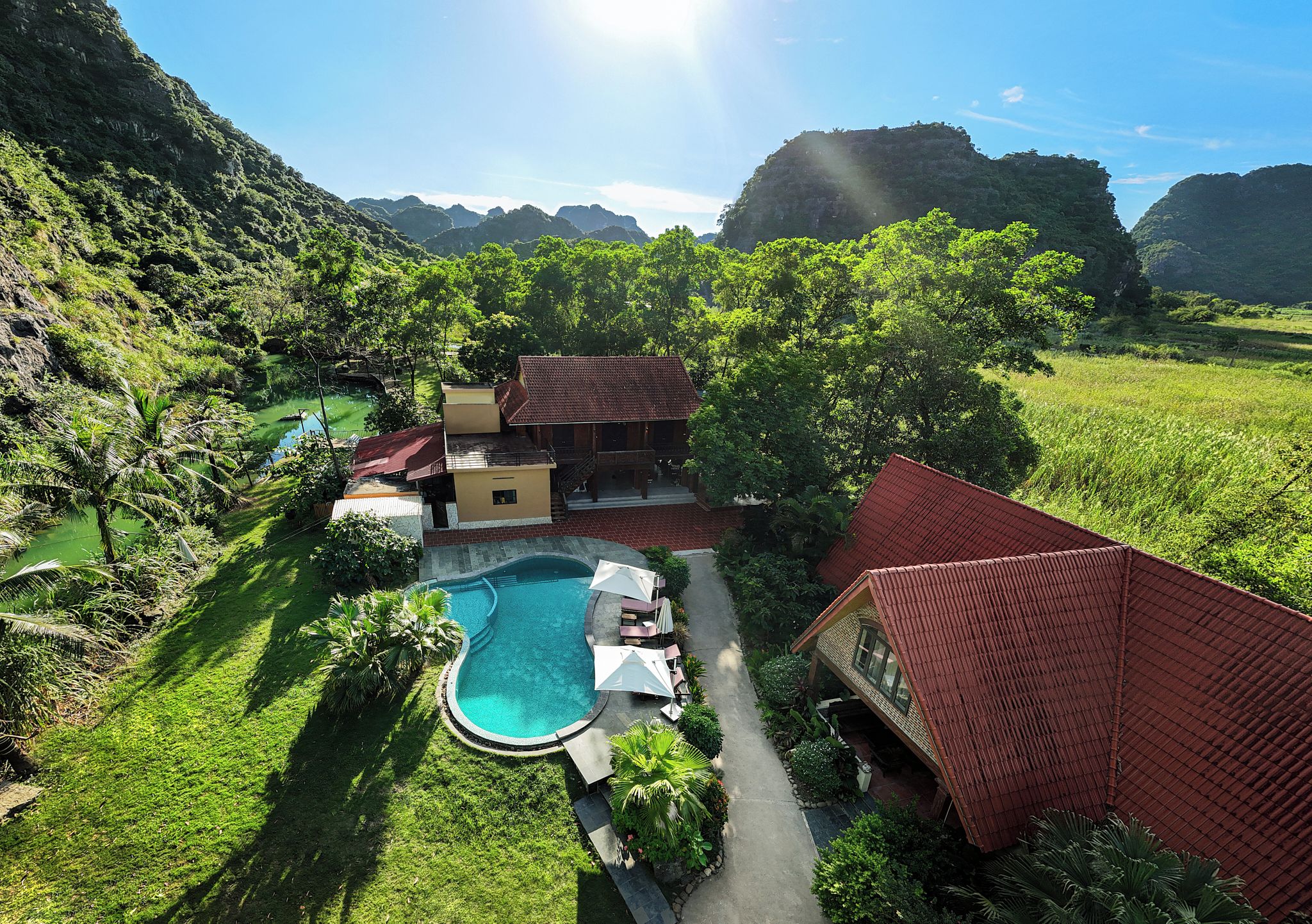 A resort with a swimming pool, surrounded by lush greenery and hills.