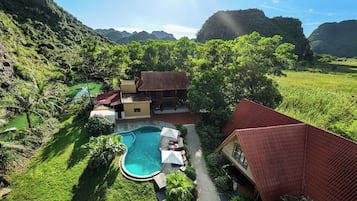 A resort with a swimming pool, surrounded by lush greenery and hills.