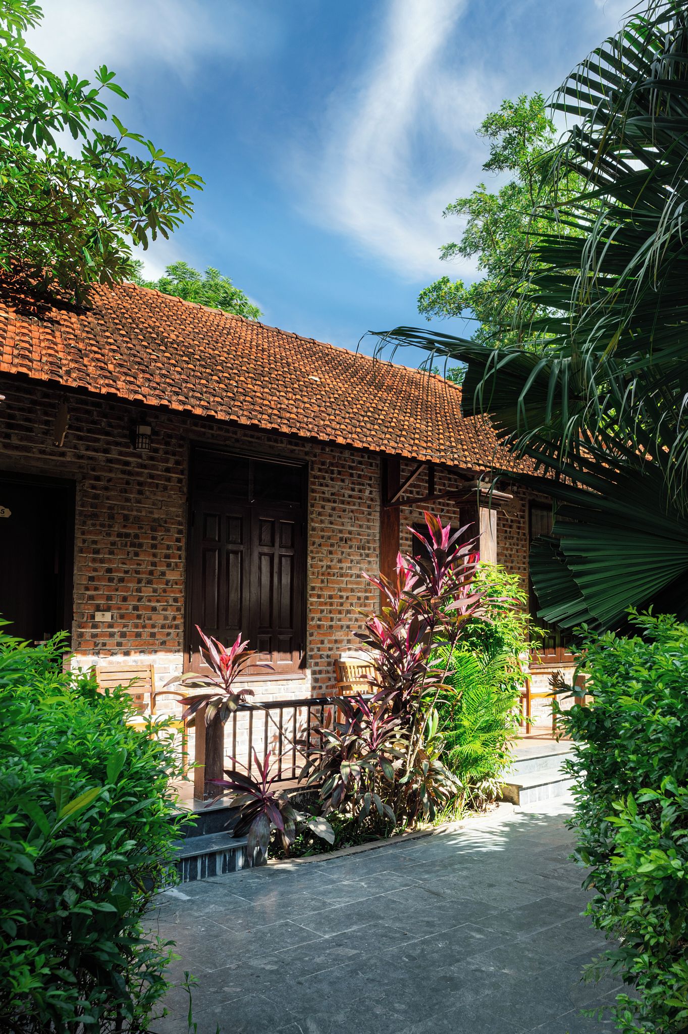 A traditional brick building with a tiled roof, a wooden door, and a small porch area.