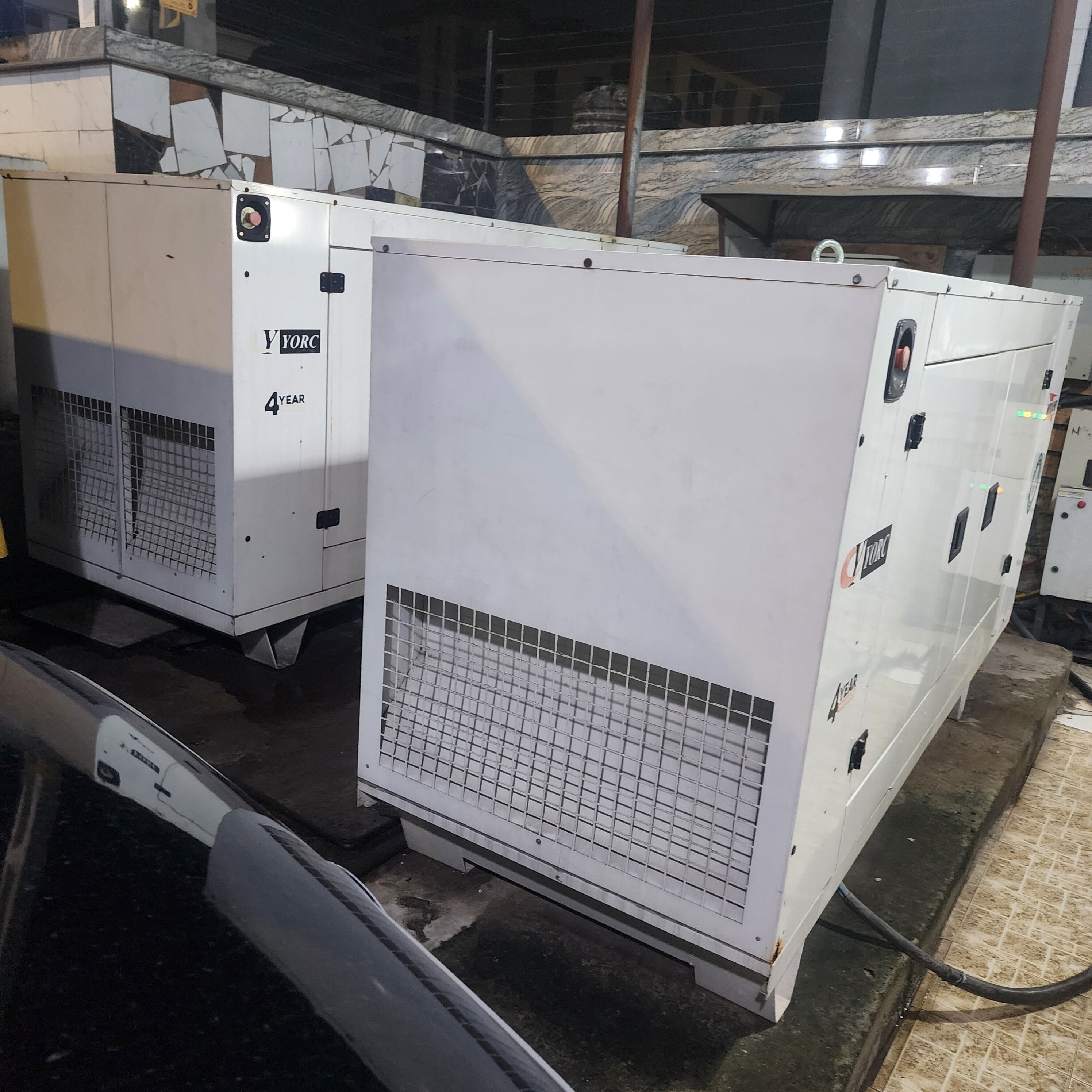 Two large industrial air conditioning units with the label "YORC 4 YEAR" on them, placed on a concrete floor with a metal grate covering the vents.