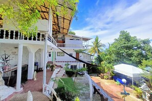 A two-story building with a balcony, a staircase, and a garden area with a palm tree. - Marcnel Bayside Resort powered by Cocotel (Oslob)