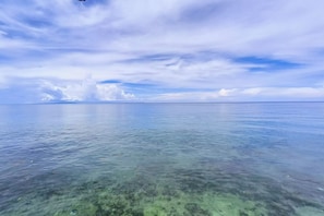 A clear view of a calm sea with a distant landmass under a partly cloudy sky. - Marcnel Bayside Resort powered by Cocotel (Oslob)