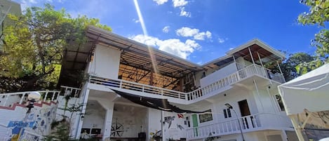 Un edificio de dos pisos con un balcón, una escalera y un letrero que dice 'Shop'.