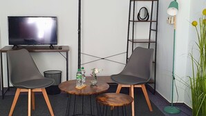 A room with a TV, two chairs, a small table, a floor lamp, and a plant. - Cozy vacation apartment Berlin for 9 people (Berlin)