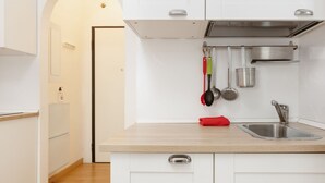 Een moderne keuken met witte kasten, een roestvrijstalen spoelbak en hangende keukengerei.