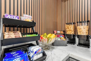 A breakfast bar with various food items and a coffee machine. - Greenleaf Hotel (Long Beach)
