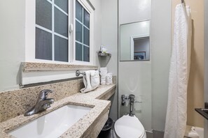 A bathroom with a sink, toilet, and a window. - Greenleaf Hotel (Long Beach)