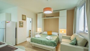 Ett hotellrum med en säng, en soffa, ett skrivbord och ett kylskåp.
