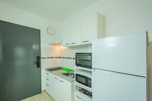 A compact kitchen with white cabinets, a microwave, a toaster, and a clock on the wall. - Spacious Apartment in Downtown Buenos Aires (Buenos Aires)