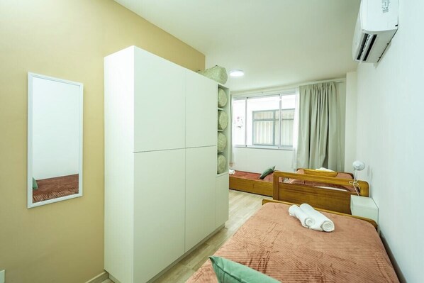 A bedroom with a bed, a wardrobe, a mirror, and an air conditioning unit.