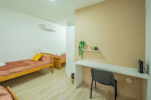 A dormitory room with two single beds, a desk, a chair, a shelf with a plant, and an air conditioning unit. - Spacious Apartment in Downtown Buenos Aires (Buenos Aires)