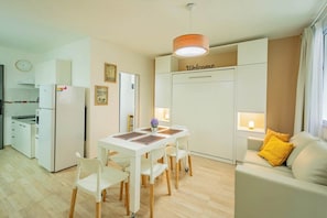 A modern kitchen with white appliances, a dining area with a white table and chairs, and a living area with a sofa and a 'Welcome' sign. - Spacious Apartment in Downtown Buenos Aires (Buenos Aires)