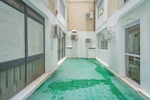 A narrow corridor with a green floor, air conditioning units, and a window on the right. - Spacious Apartment in Downtown Buenos Aires (Buenos Aires)