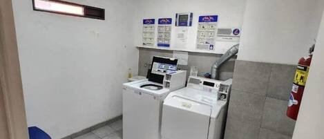 A laundry room with a washing machine, dryer, and a blue chair.