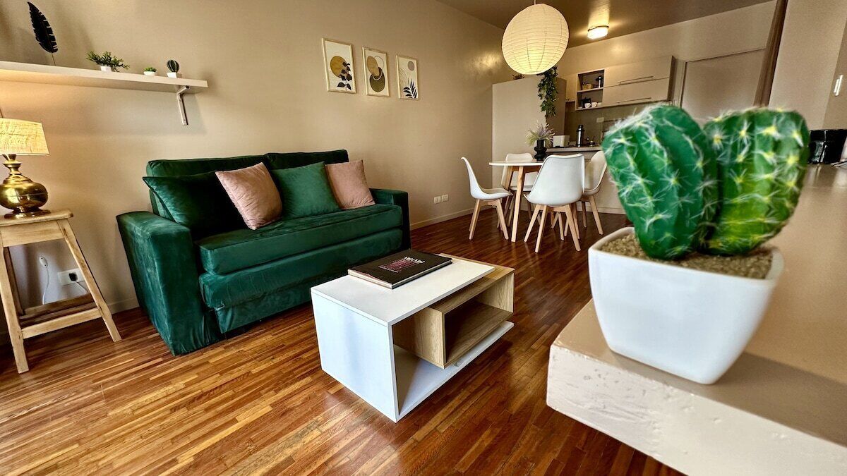 Una sala de estar moderna con un sofá verde, una mesa de centro y un comedor con sillas y una mesa.