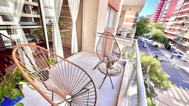 Een balkon met twee rieten stoelen en een bloempot.