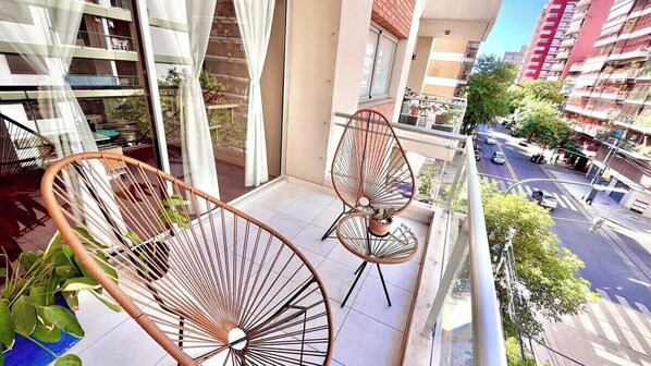 A balcony with two wicker chairs and a potted plant.