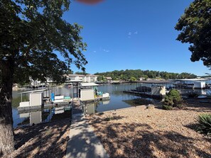 A marina with docked boats, a pathway, and buildings in the background.