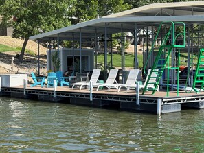 A covered dock with lounge chairs and a pool table.