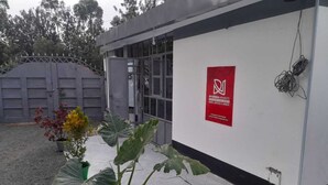 Ein Gebäude mit rotem Schild, Topfpflanze und einem verschlossenen Eingang.