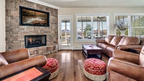 A living room with a stone fireplace, leather sofas, and ottomans. - Lakefront - Unbelievable 3 levels w/Elevator! (Dandridge)