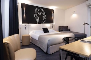 A hotel room with a bed, a desk, a chair, a sofa, and a wall-mounted artwork. - Bridgestreet Montparnasse / St Germain (Paris)