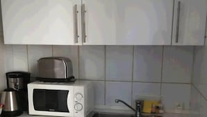 A kitchen with white cabinets, a toaster, a coffee maker, and a sink. - Bridgestreet Montparnasse / St Germain (Paris)