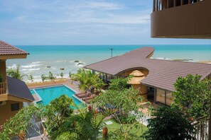 A resort with a swimming pool, beach view, and tropical landscaping.