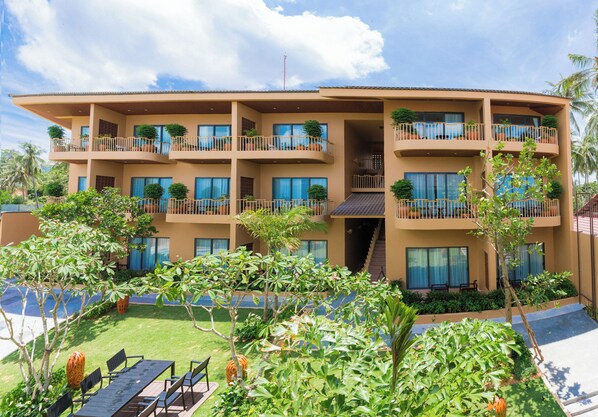 A multi-story hotel with balconies, a swimming pool, and lush landscaping.