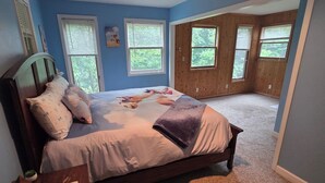 A bedroom with a bed, a nightstand, a window, and a door leading to an outdoor area.