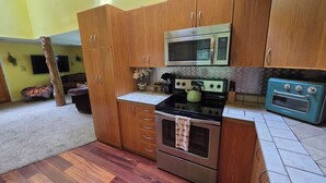A kitchen with wooden cabinets, a microwave, a stove, and a vintage oven.