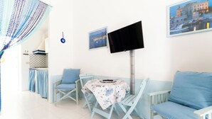 A room with a table and chairs, a flat-screen TV mounted on the wall, and two framed pictures. - Jewel within walking distance of the CENTER (Favignana)