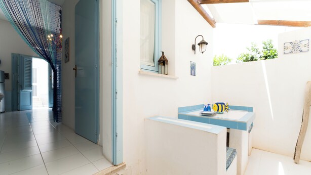 A hallway with a blue door, a small window with a lantern, and a blue and white sink area. - Jewel within walking distance of the CENTER (Favignana)