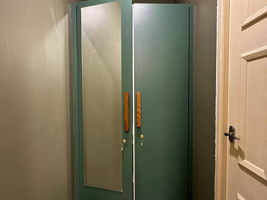 Puerta verde cerrada con picaporte de madera y cerradura.